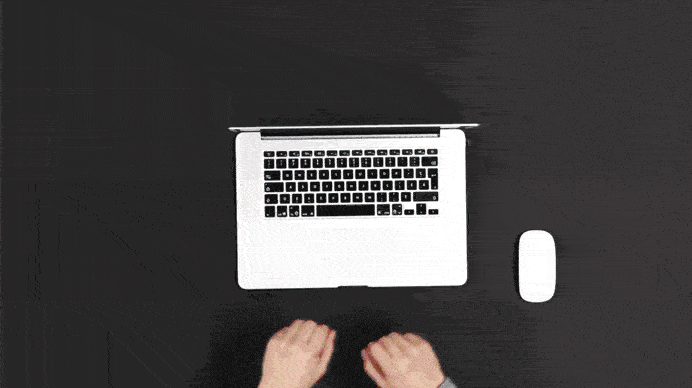 Top view of hands typing on a white laptop keyboard with a white mouse beside it on a black surface